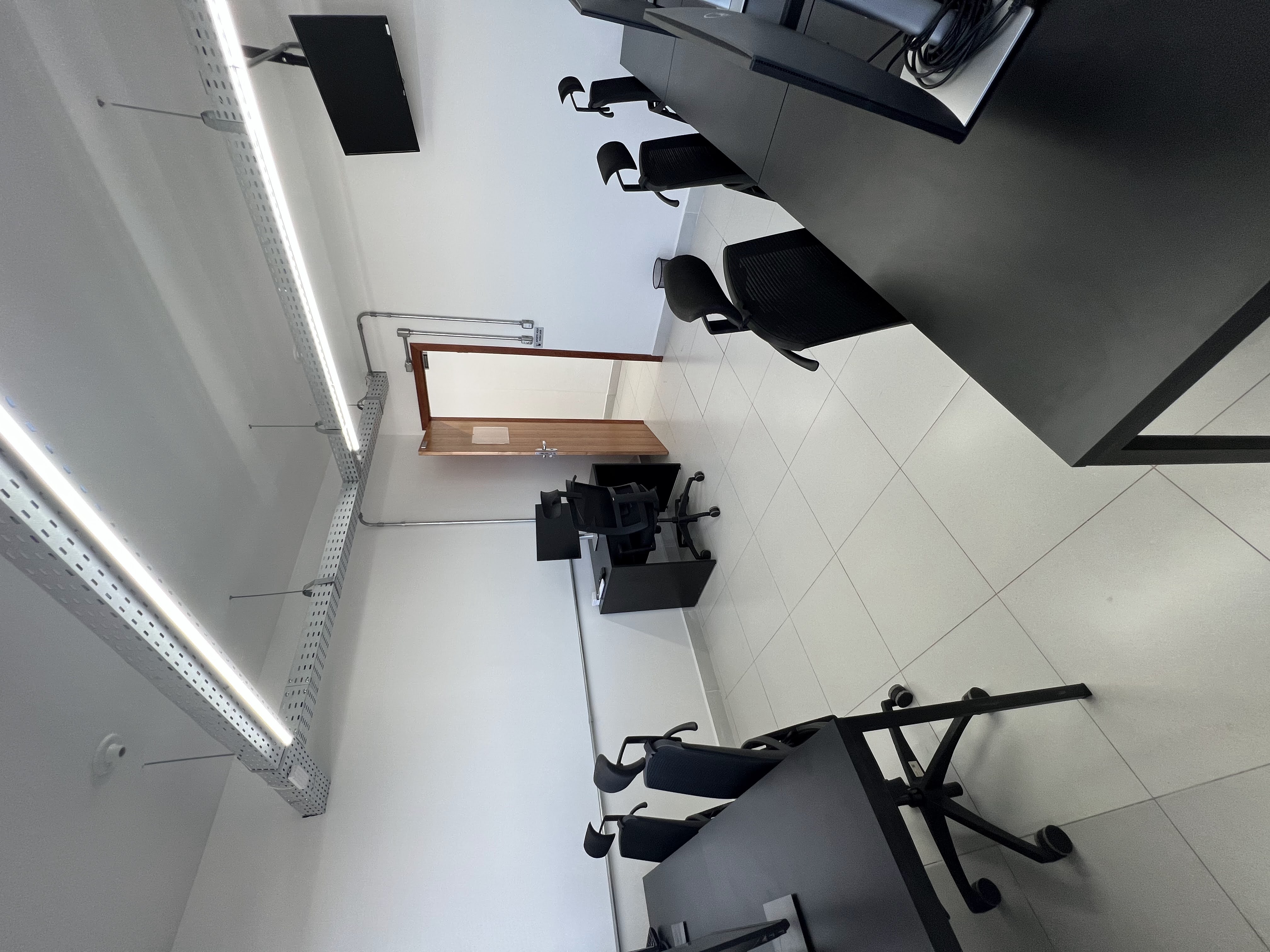 Sala privativa com porta de madeira, TV e mesas de trabalho no Inconfidência em Betim